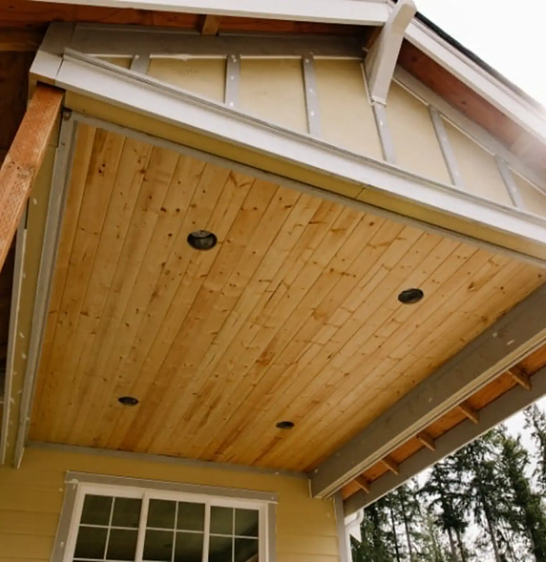 Wood-paneled soffit under a house roof overhang with recessed lights