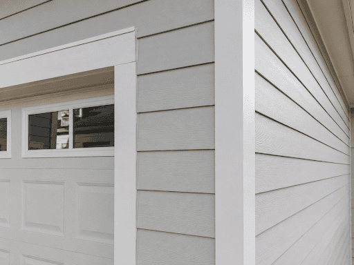 A close-up of fiber cement trim and siding installed around a residential garage exterior.