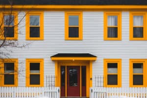 A house with white siding and vibrant yellow trim around the door and windows.